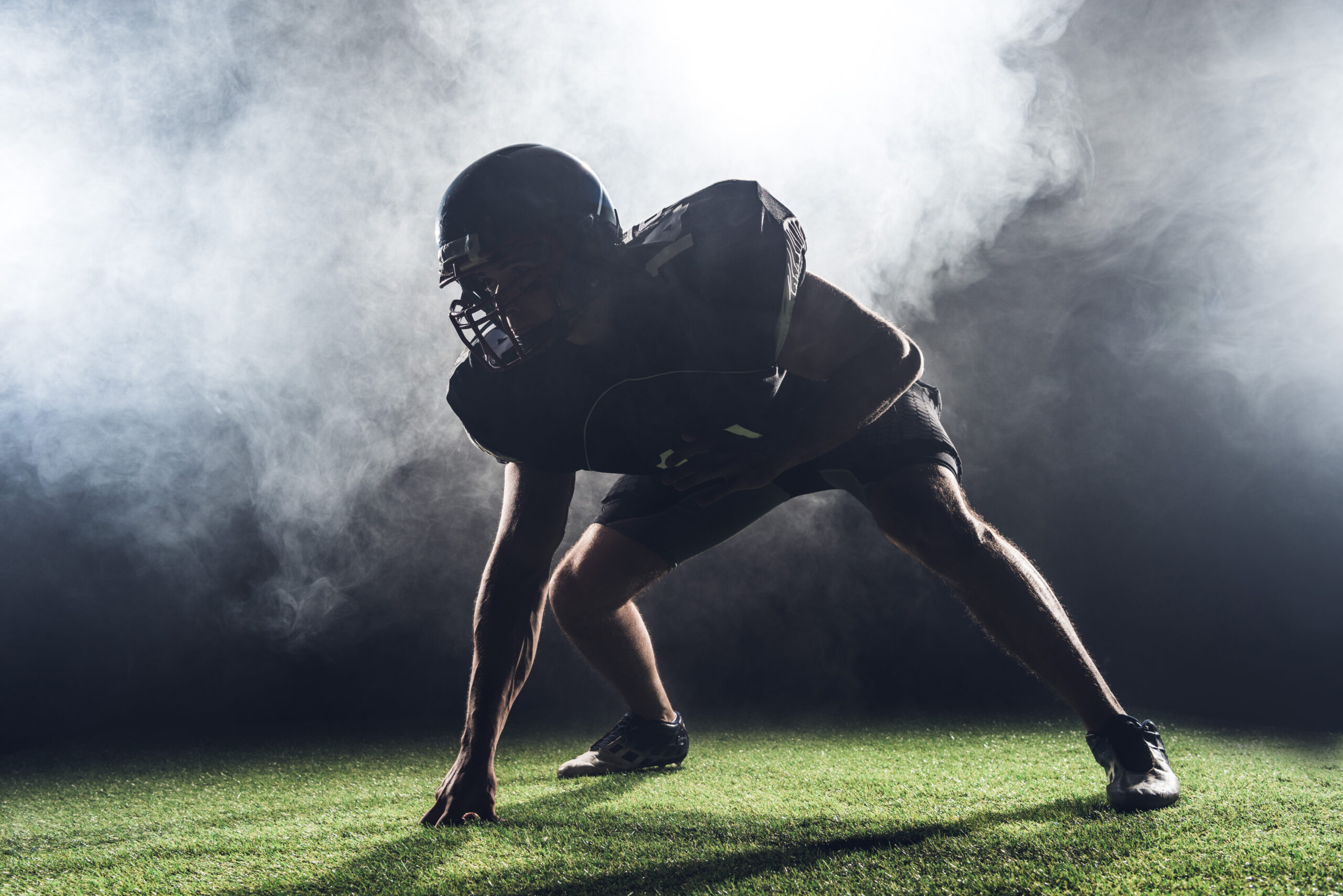 silhouette of american football player in star position against white smoke